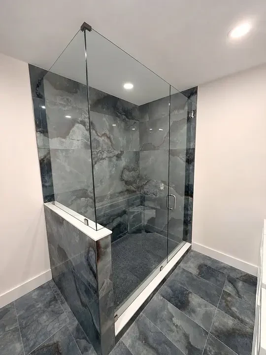 Custom glass shower enclosure with marble-look tile.